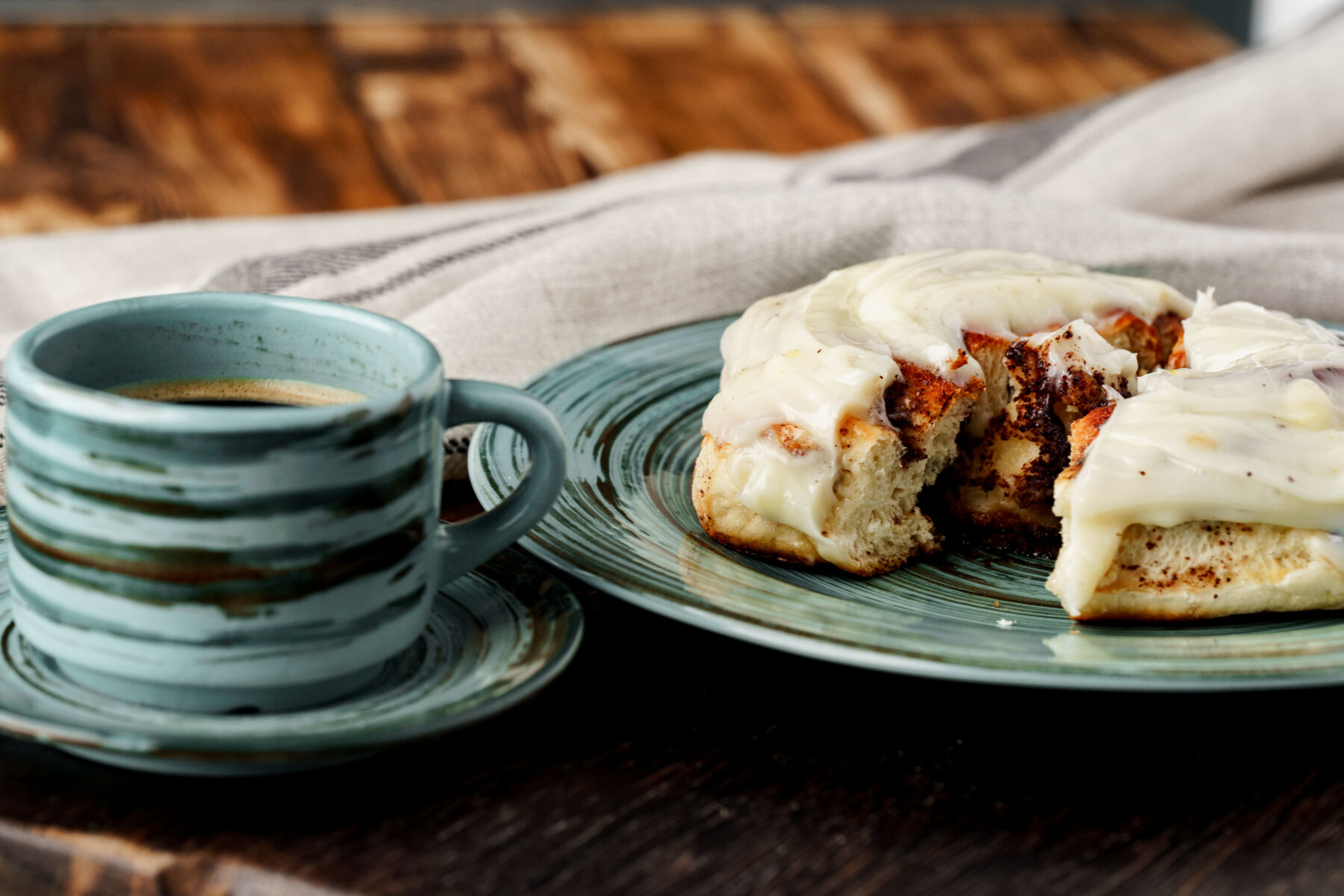 glazed-cinnabon-bun-in-green-plate-on-wooden-table-2023-11-27-05-18-26-utc.jpg